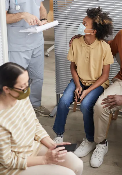 african-american family wearing masks and looking at doctor