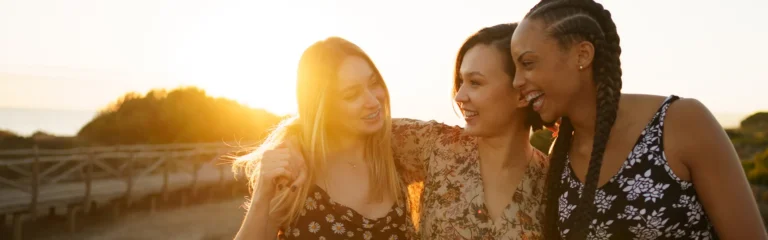 Smiling migrant friends standing against sky